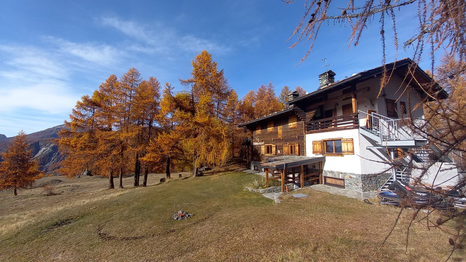Le chalet L'Ermitage entouré de mélèzes aux couleurs dorées de l'automne.