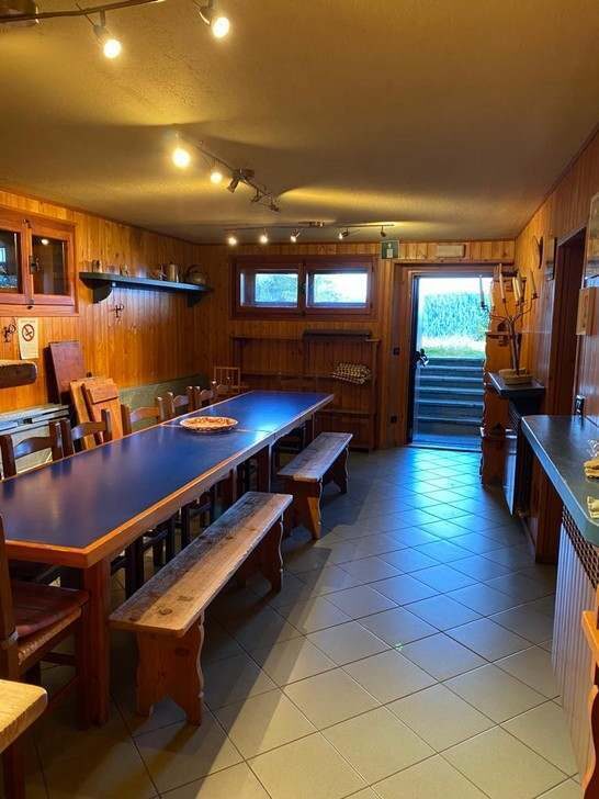 Salle polyvalente à l'entresol avec longue table et bancs.